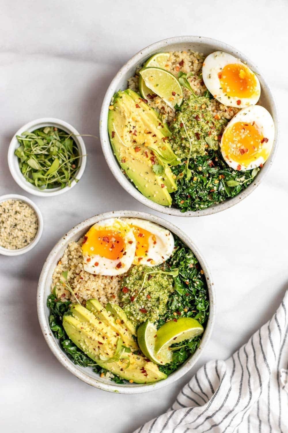 Two wholesome grain bowls with greens, avocado and egg