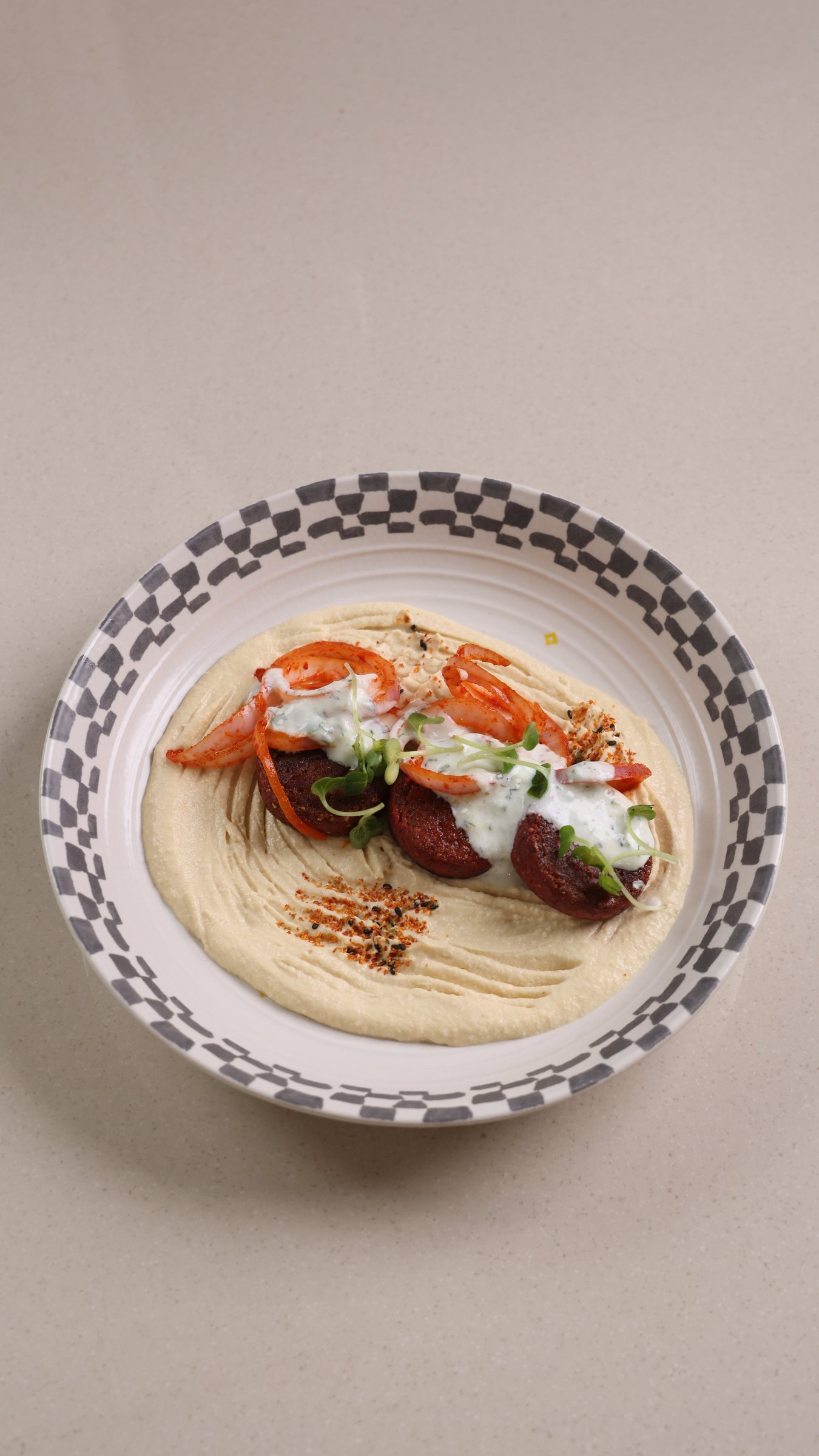 Beetroot falafel over hummus on a checkered plate