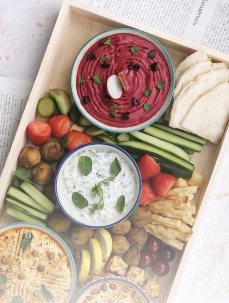 A grazing board of beetroot hummus, dips, pita and crudités